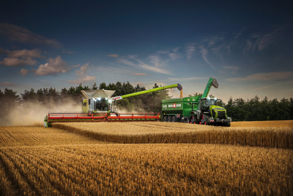 zdjęcie dwóch maszyn rolniczych; obie maszyny są na polu ze zbożem;kombajn marki CLAAS przesypuje skoszone na przyczepę;skup zbóż Krasnystaw;